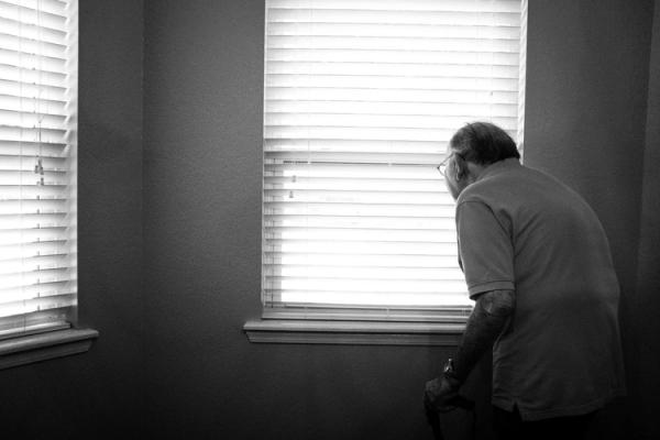 Elderly person looking out of window