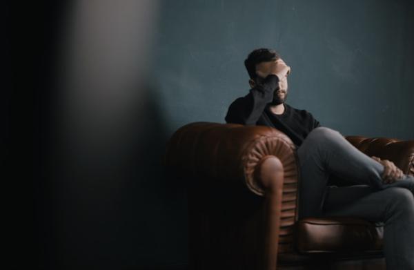 Man holding head sitting on couch